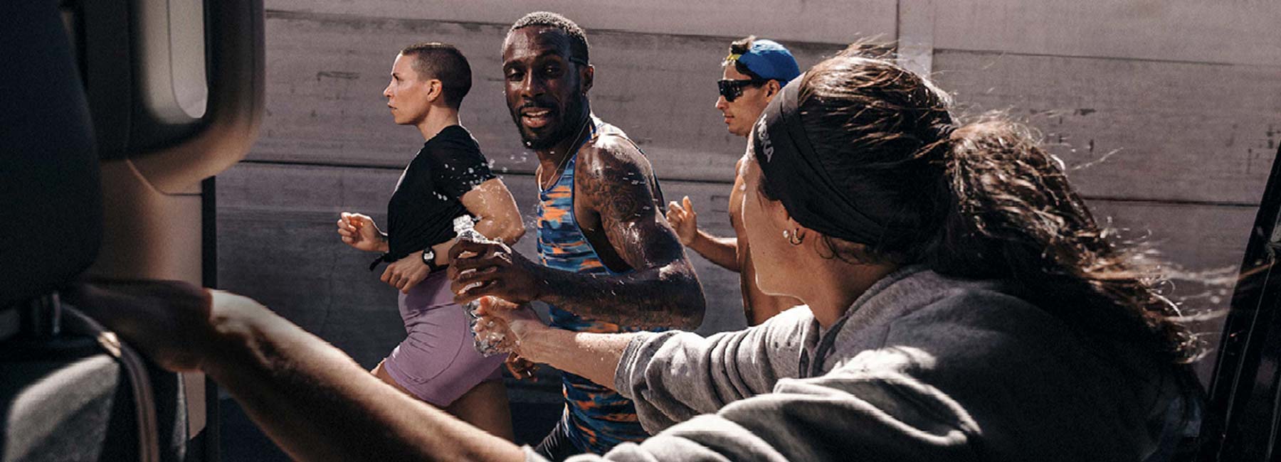 HOKA runners getting water from bystander on the road.